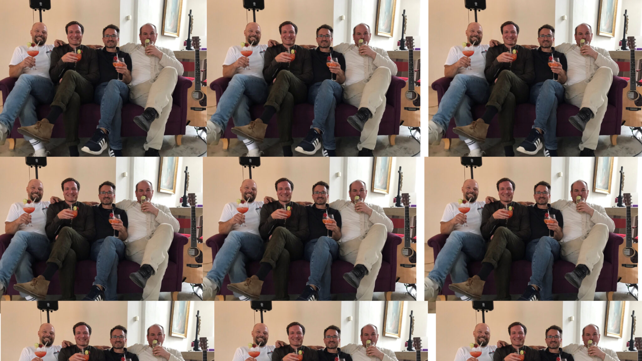 Vier Männer sitzen entspannt mit Drinks auf einem lila Sofa.